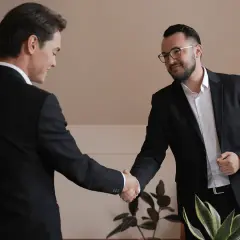Two businessmen in suits shake hands, a successful outcome of their learning negotiation.