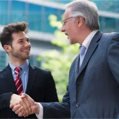 Two businessmen shake hands, symbolizing a smooth succession planning for their family business.