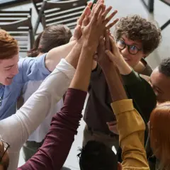 A diverse group of colleagues celebrates a successful corporate volunteering event with a high-five huddle.