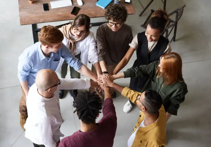 A diverse team joins hands, symbolizing unity and why respect is important for collaboration and shared success.