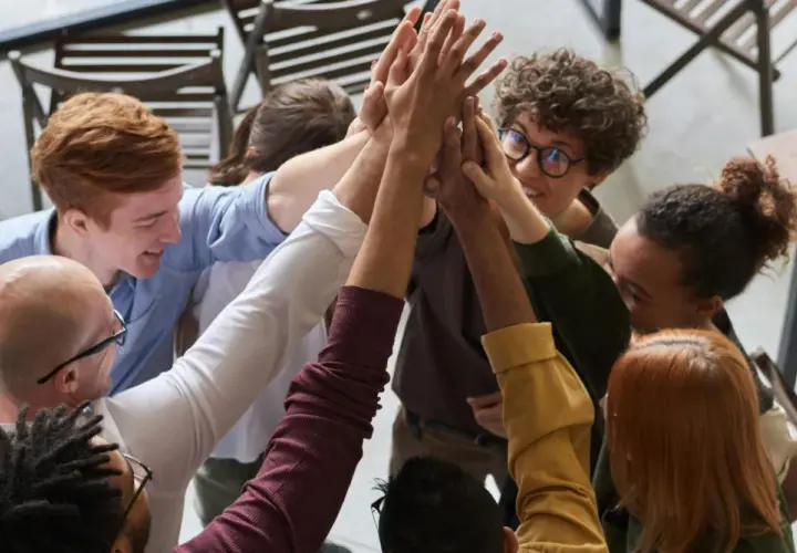 A diverse group of colleagues celebrates a successful corporate volunteering event with a high-five huddle.