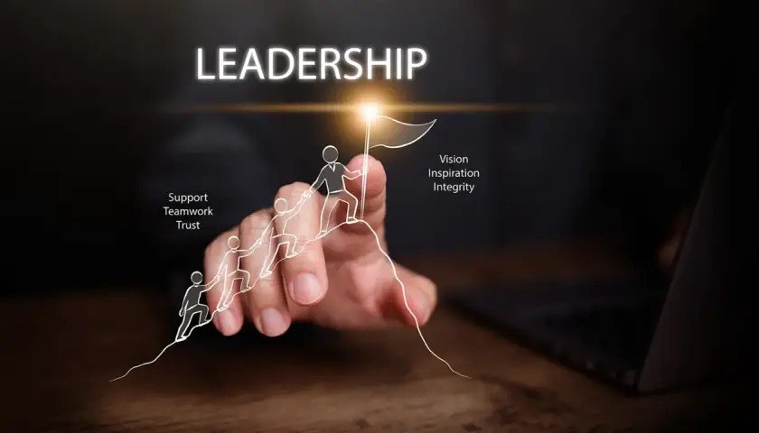 A hand guides a drawn team up a mountain, symbolizing leadership development. Key traits like vision, inspiration, integrity, support, teamwork, and trust are highlighted.