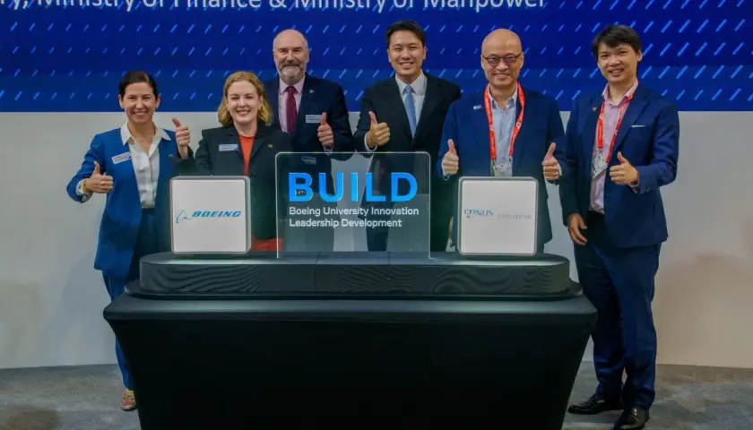 Six individuals in suits give thumbs up at a ceremony for Boeing University Innovation Leadership Development.