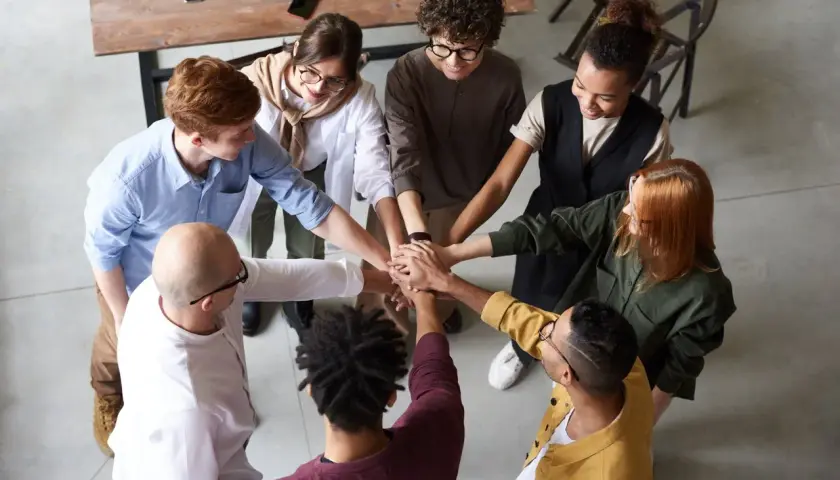 A diverse team joins hands, symbolizing unity and why respect is important for collaboration and shared success.