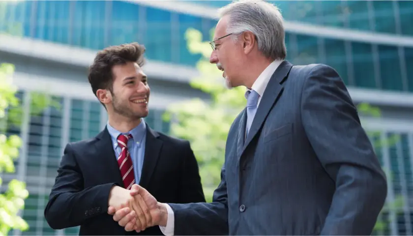 Two businessmen shake hands, symbolizing a smooth succession planning for their family business.
