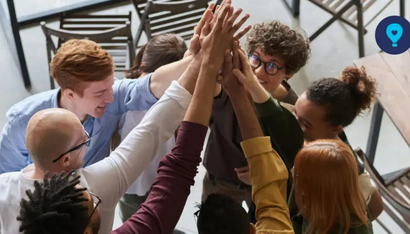 A diverse group of colleagues celebrates a successful corporate volunteering event with a high-five huddle.