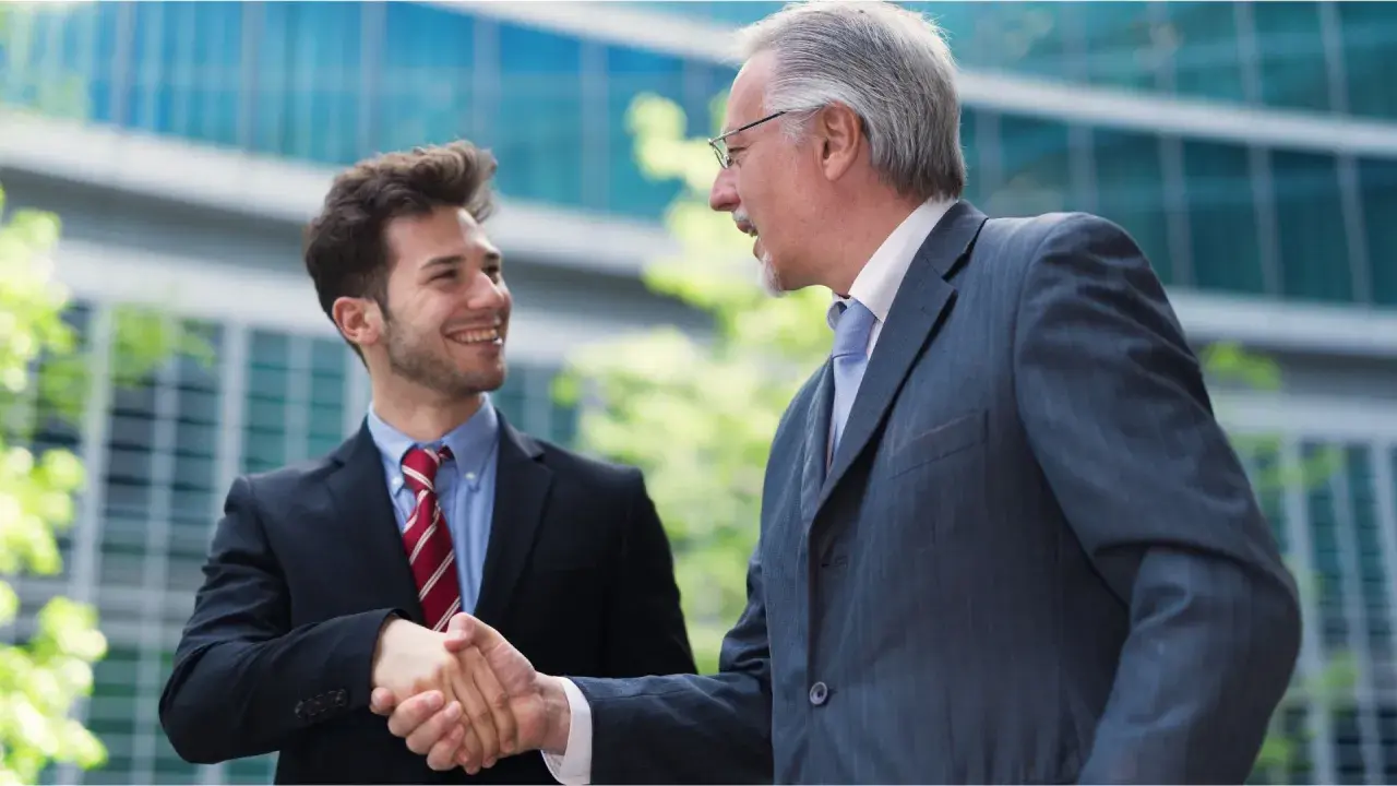 Two businessmen shake hands, symbolizing a smooth succession planning for their family business.