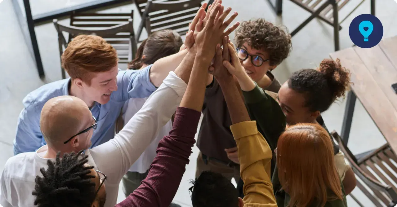 A diverse group of colleagues celebrates a successful corporate volunteering event with a high-five huddle.
