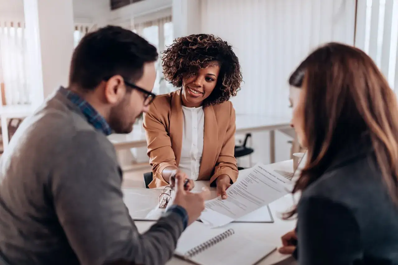 A woman smiles as she hands a contract to a man, suggesting a discussion about whether you should always negotiate salary.