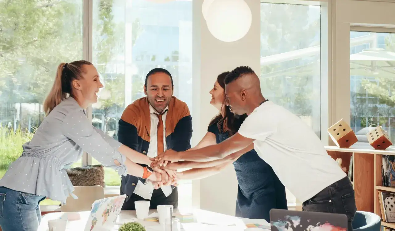 A diverse team joins hands in a circle, symbolizing a strong leadership culture built on collaboration and shared success.