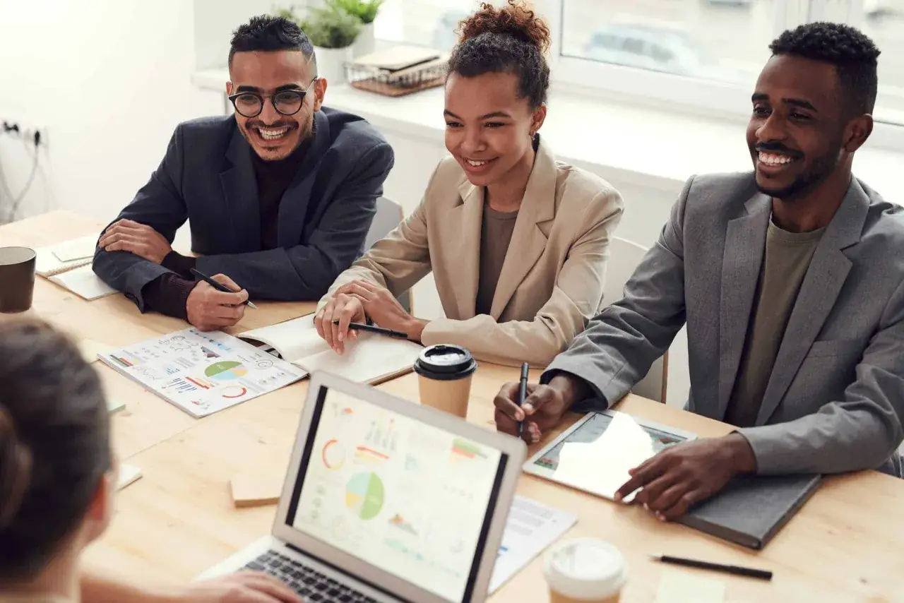 A diverse team collaborates, discussing charts and data. This scene illustrates how to improve listening skills by actively engaging in meetings and understanding diverse perspectives.