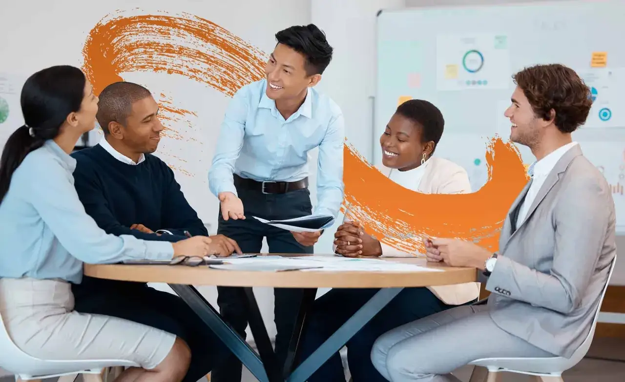 A diverse team collaborates around a table, discussing documents. This scene exemplifies leadership development, fostering growth and teamwork.