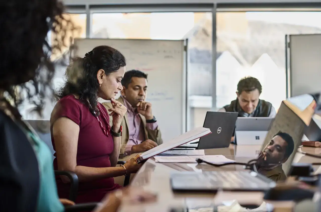 Participants in a Berkeley Technology Leadership Program meeting review documents and engage with laptops.