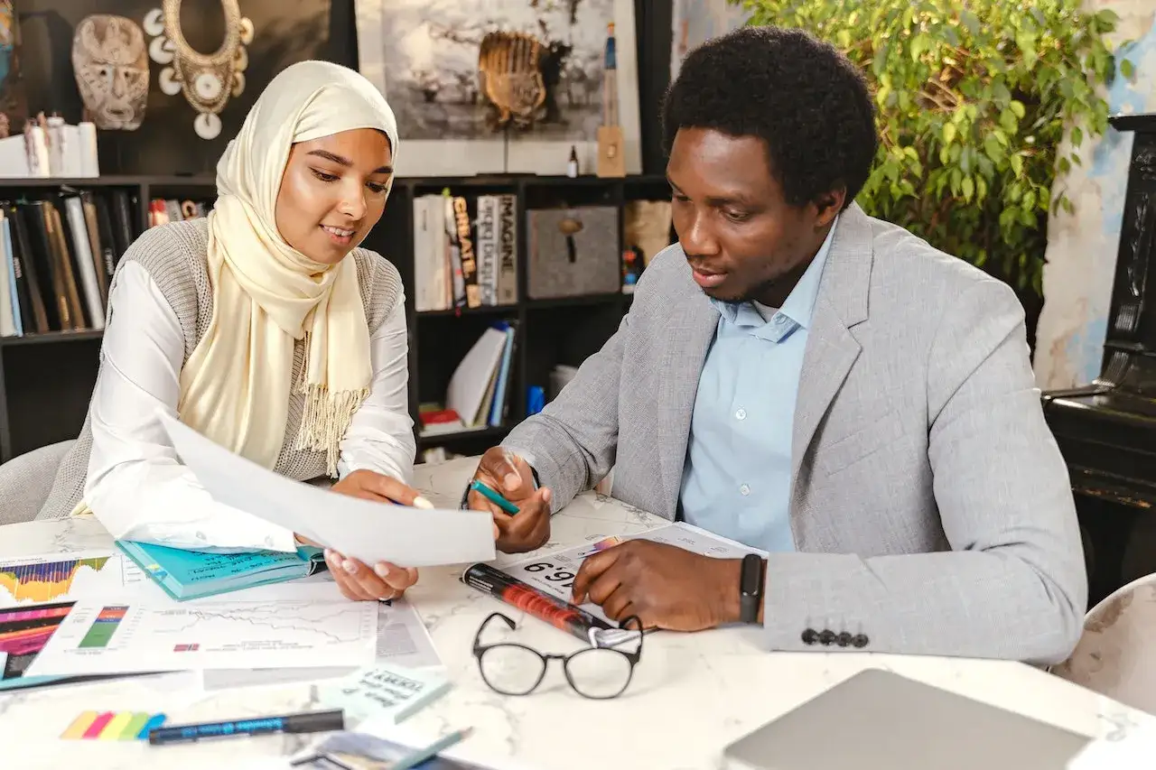 A man and woman review documents, discussing how to give negative feedback constructively.